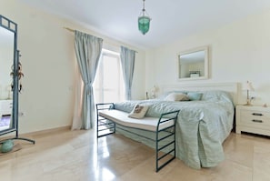 Une chambre à coucher comprenant un lit, une table de chevet, un miroir et un luminaire suspendu.