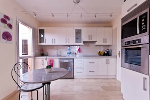A modern kitchen with white cabinets, a dishwasher, and a built-in oven.