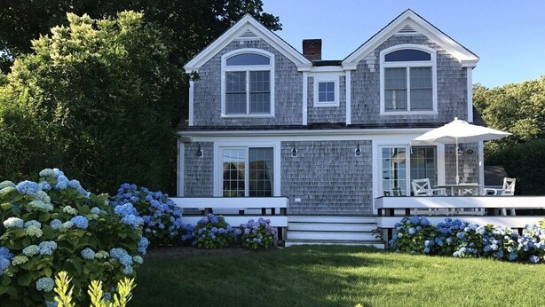 Une maison à deux étages dotée d’un patio couvert.