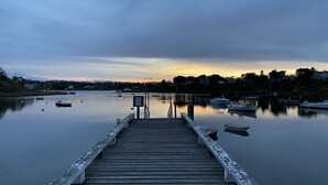 Une jetée en bois qui s’avance dans une étendue d’eau calme, avec des bateaux amarrés à proximité.