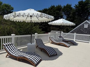 A sun deck with striped lounge chairs and white umbrellas. - Experience a relaxing vacation at this beautifully maintained estate! (Chatham)