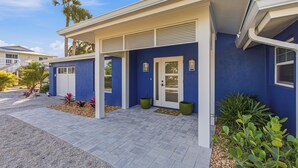 Una casa moderna con facciata blu, un portico coperto e una porta d'ingresso con pannello in vetro.