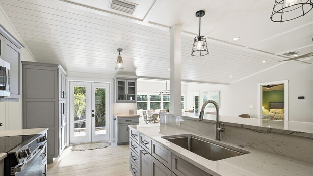 Una cucina moderna con una grande isola, elettrodomestici integrati e vista sul patio esterno.