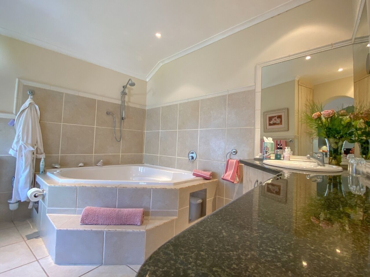 A modern bathroom with a large bathtub, a vanity with a mirror, and a sink.