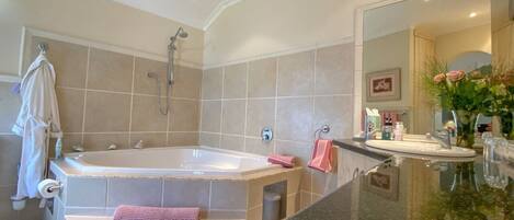 A modern bathroom with a large bathtub, a vanity with a mirror, and a sink.
