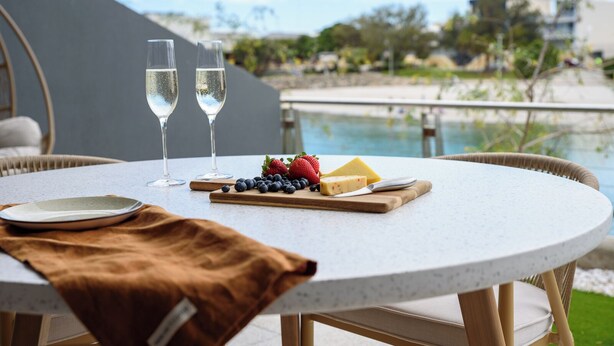 A round table with a white speckled tablecloth, two glasses of champagne, a plate, a wooden board with cheese, strawberries, and blueberries, and a brown cloth. - Waterfront Retreat-North Coogee, beachfront,Sauna, family friendly, Fremantle (North Coogee)