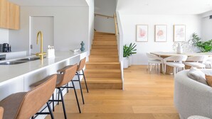 A modern kitchen with a wooden staircase leading to a dining area. - Waterfront Retreat-North Coogee, beachfront,Sauna, family friendly, Fremantle (North Coogee)