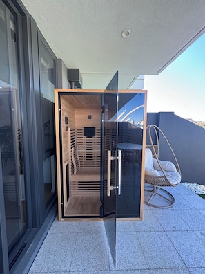Un espacio exterior moderno con pared de vidrio, interior de madera y una silla colgante.