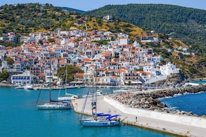 A coastal town with white buildings and red roofs, a marina with sailboats, and a rocky shoreline. - Stolios Skopelos - Clio Superior Panoramic Seaview (Skopelos)