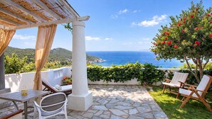 Eine Terrasse mit Steinböden, weißen Möbeln und Blick aufs Meer.