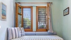 Ein Zimmer mit einem hölzernen Bett, einem Fenster mit Vorhängen und einem Wandbild.
