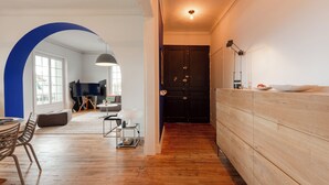 A modern living room with a wooden floor, a large TV on a stand, a sofa, and a dining area with chairs. - MISVA • KEYWEEK Architect-designed flat in Biarritz with garden (Biarritz)