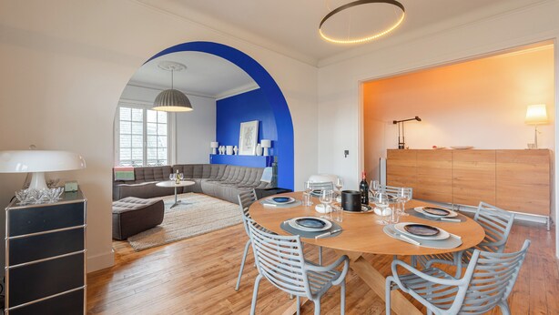 A modern dining area with a wooden table set for six, surrounded by white chairs. - MISVA • KEYWEEK Architect-designed flat in Biarritz with garden (Biarritz)