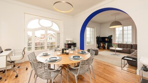 A modern living room with a round dining table set for four, a large flat-screen TV, and a cozy seating area with a sofa and armchairs. - MISVA • KEYWEEK Architect-designed flat in Biarritz with garden (Biarritz)