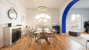 A dining area with a round table, chairs, a fireplace, and a view through a large window. - MISVA • KEYWEEK Architect-designed flat in Biarritz with garden (Biarritz)