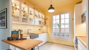 A kitchen with white cabinets, a wooden countertop, and a window with a view of buildings. - MISVA • KEYWEEK Architect-designed flat in Biarritz with garden (Biarritz)