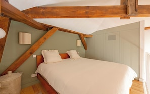 A bedroom with a wooden ceiling, a bed with white bedding, a wall-mounted lamp, and a window with blinds. - EUGENIE - Apt with balcony and sea view and Hotel du Palais in Biarritz (Biarritz)