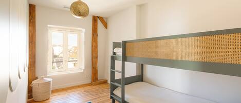 Habitación con literas, ventana, piso de madera y lámpara colgante.
