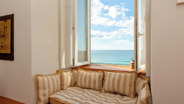 A room with a large window overlooking the sea, a woven sofa, and a framed artwork on the wall. - EUGENIE - Apt with balcony and sea view and Hotel du Palais in Biarritz (Biarritz)
