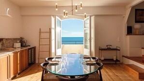 A dining area with a glass table, chairs, and a view of the sea. - EUGENIE - Apt with balcony and sea view and Hotel du Palais in Biarritz (Biarritz)
