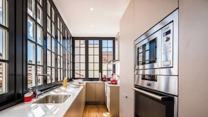 Une cuisine moderne dotée d’une grande fenêtre, d’appareils électroménagers en acier inoxydable et d’un plancher en bois.