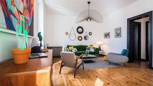 Un salon moderne avec un canapé vert, une table basse en bois et un ventilateur de plafond original.