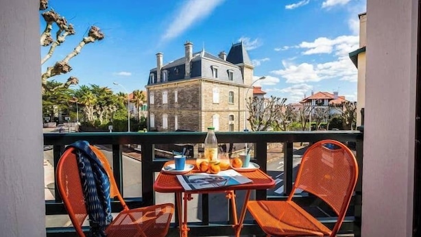Un balcon avec une table et des chaises, donnant sur un bâtiment historique.