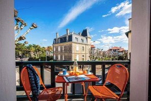 Een balkon met een tafel en stoelen, met uitzicht op een historisch pand.