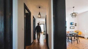 Un couloir au plancher de bois menant à une salle à manger équipée d’une table et de chaises.