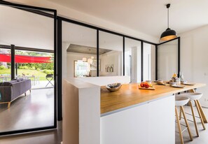 Una cocina moderna con encimera de madera, armarios blancos y un ventanal grande.