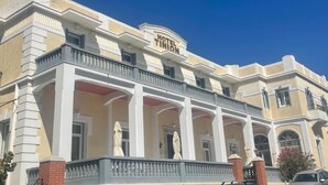 A hotel with a classic architectural style, featuring a prominent balcony and a sign that reads "HOTEL TINION". - Tinion Urban Hotel (Tinos)