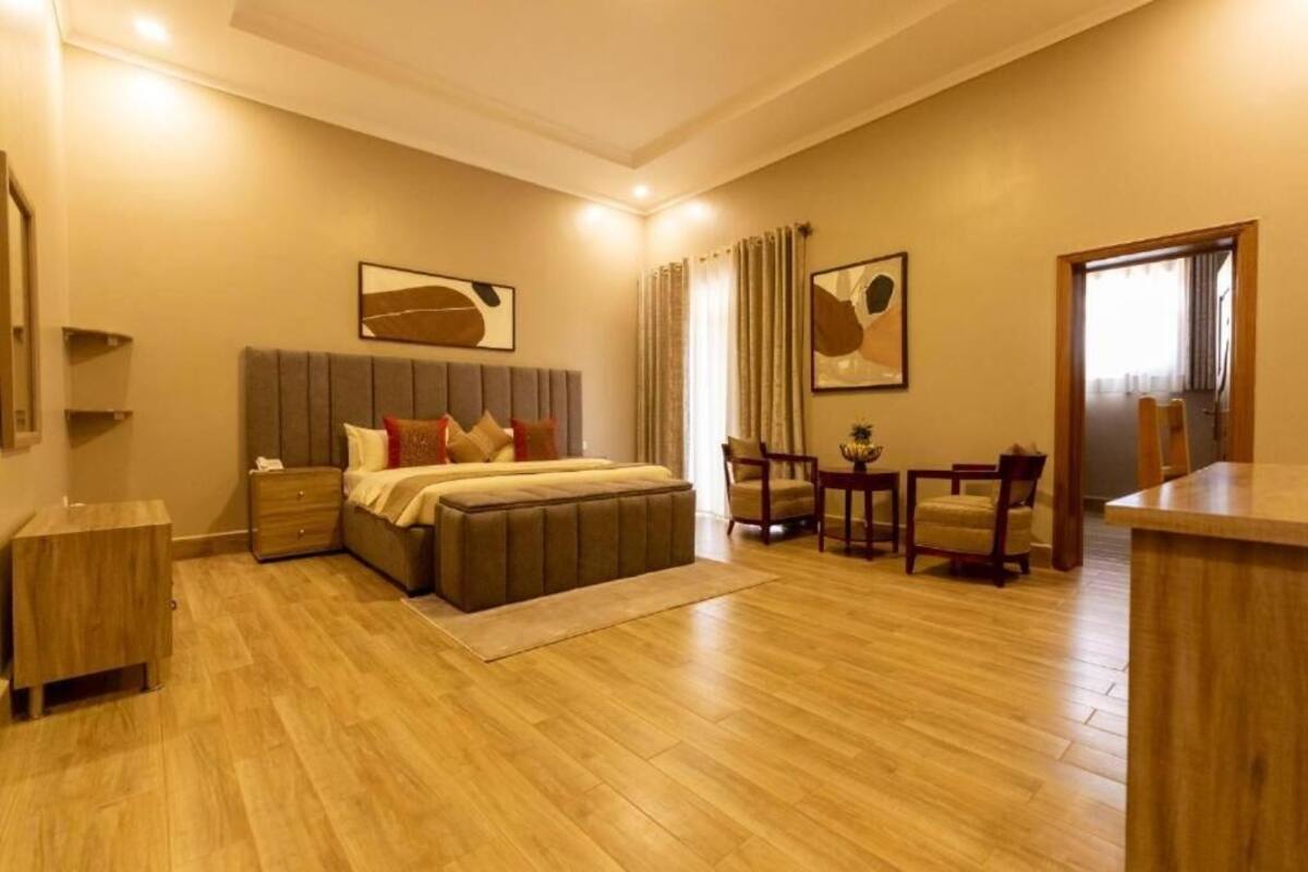 Un dormitorio amplio con una cama grande, mesitas de noche, un escritorio y sillas.