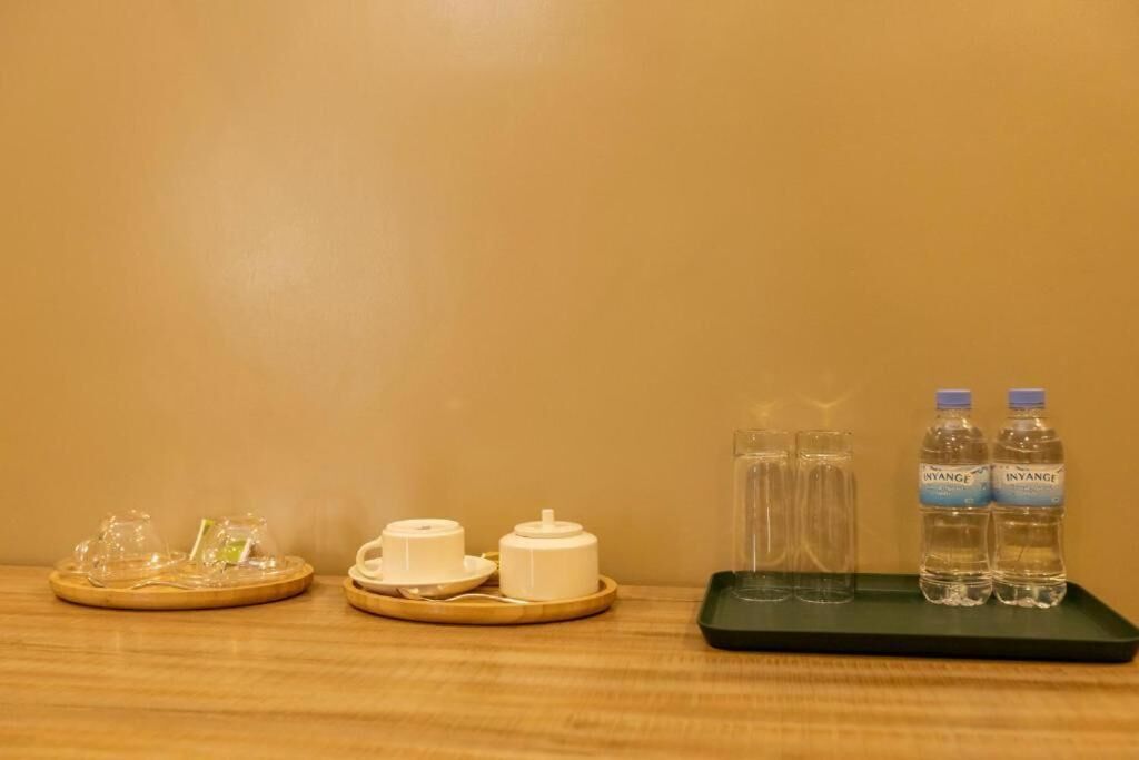 A wooden table with a tea set, two glass tumblers, and two bottles of water.