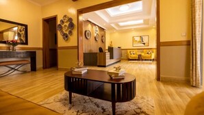 Un hall de hotel con un mostrador de recepción de madera, una consola negra y un sofá amarillo.