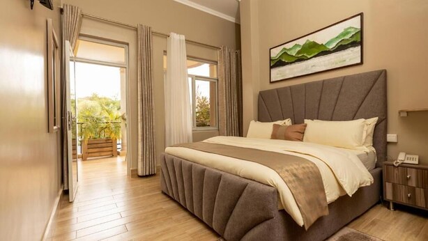 Un dormitorio con una cama grande, una mesita de noche y una ventana con cortinas.
