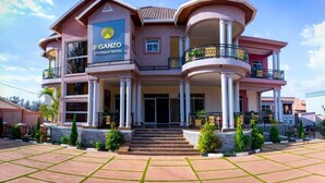 Un hotel de varios pisos con un logotipo destacado, una entrada imponente y un balcón con barandillas decorativas.