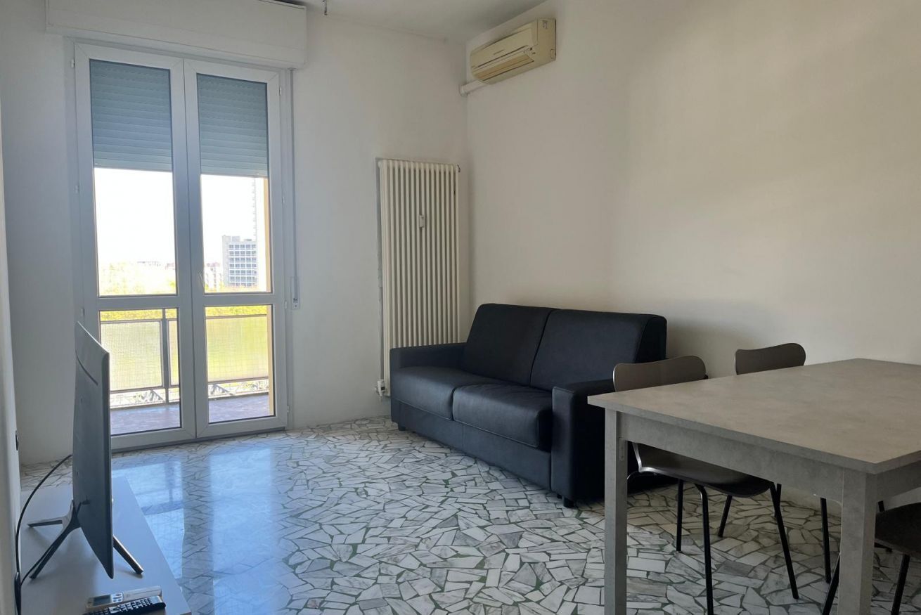 Una habitación con suelo de baldosas, un sofá, una mesa y un televisor.