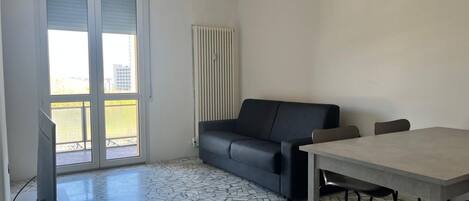 Una habitación con suelo de baldosas, un sofá, una mesa y un televisor.