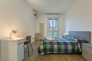 Un dormitorio con cama, escritorio, silla y radiador.