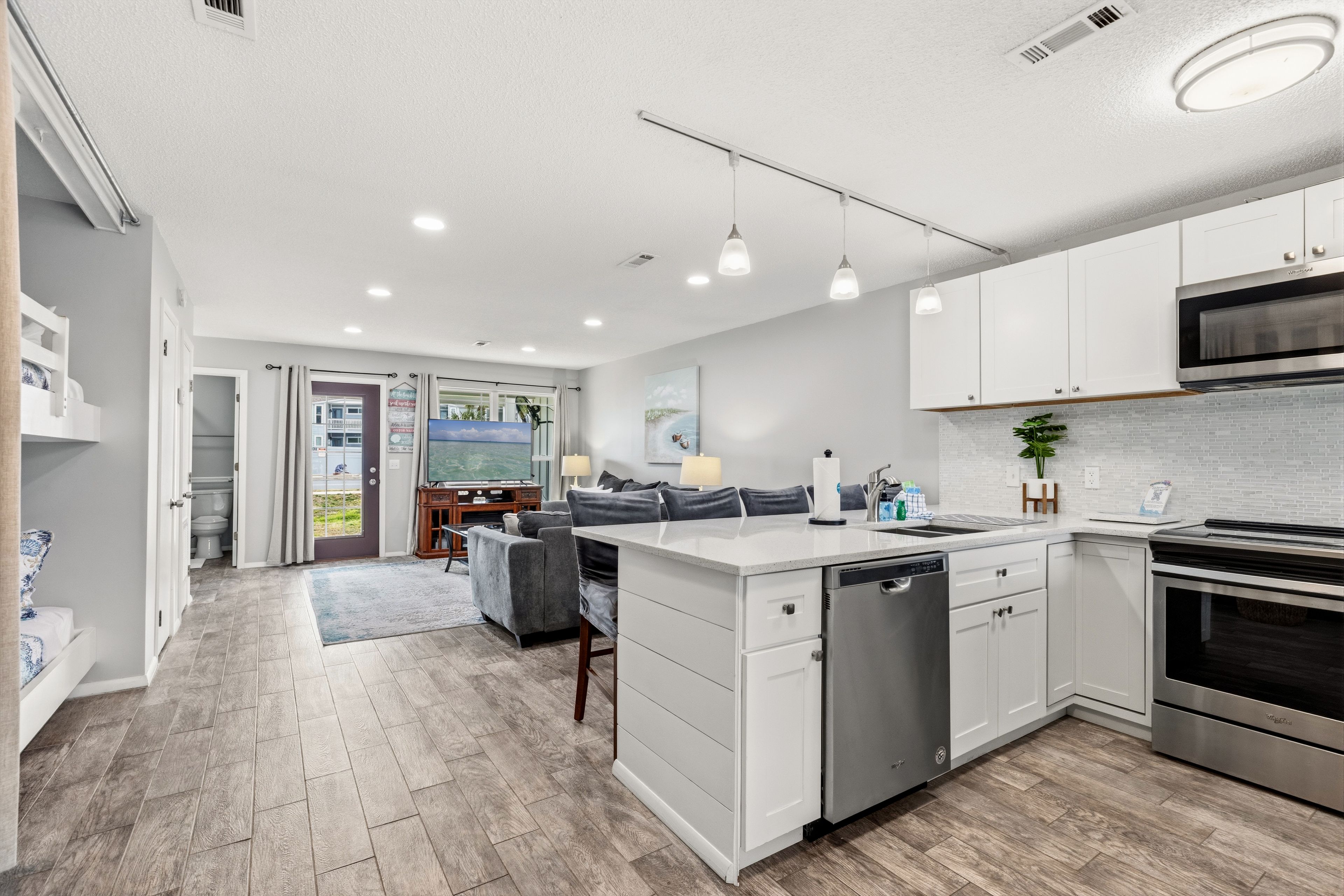 A modern kitchen with white cabinets, a built-in dishwasher, and a stainless steel oven.
