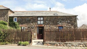 A stone house with a wooden fence, a door, and a small window. - Applestore (Wadebridge)