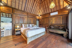 Ein schlafreiches Zimmer im Holzstil mit Bett, Nachttischen, einer Bank und einer Hängeleuchte.