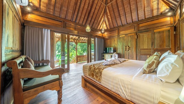 A wooden-themed bedroom with a bed, a bench, and a TV. - Saughina Ubud Tranquil Ubud Villa With Private Infinity Pool and Jungle Views (Ubud)
