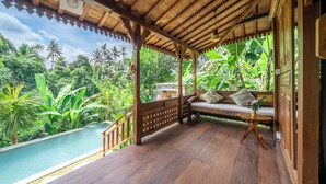 A wooden deck with a bench and a small table, overlooking a pool and lush greenery. - Saughina Ubud Tranquil Ubud Villa With Private Infinity Pool and Jungle Views (Ubud)
