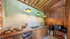 A rustic kitchen with wooden cabinets, a built-in stove, and hanging pendant lights. - Saughina Ubud Tranquil Ubud Villa With Private Infinity Pool and Jungle Views (Ubud)