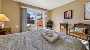 A bedroom with a large bed, a chair, a cabinet, and a sliding glass door leading to a backyard. - 2253 Catalina Drive 4 Bedroom Home (South Lake Tahoe)