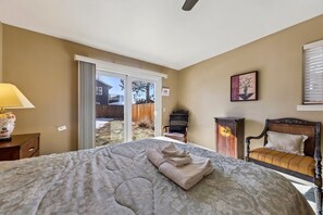 A bedroom with a large bed, a chair, a cabinet, and a sliding glass door leading to a backyard. - 2253 Catalina Drive 4 Bedroom Home (South Lake Tahoe)