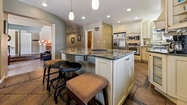 A modern kitchen with a central island, bar stools, stainless steel appliances, and a view into the living area. - 2253 Catalina Drive 4 Bedroom Home (South Lake Tahoe)