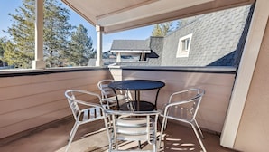 A covered balcony with a round table and four chairs, overlooking a residential area with houses and trees. - 2253 Catalina Drive 4 Bedroom Home (South Lake Tahoe)