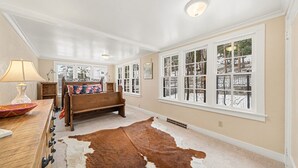 A room with a wooden bench, a cowhide rug, and large windows with a view of trees. - Twin Fawns 2 Bedroom Cabin (Estes Park)